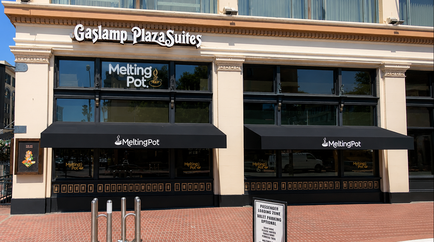 Two long black restaurant awnings with printed logos on a historic Gaslamp Quarter building facade